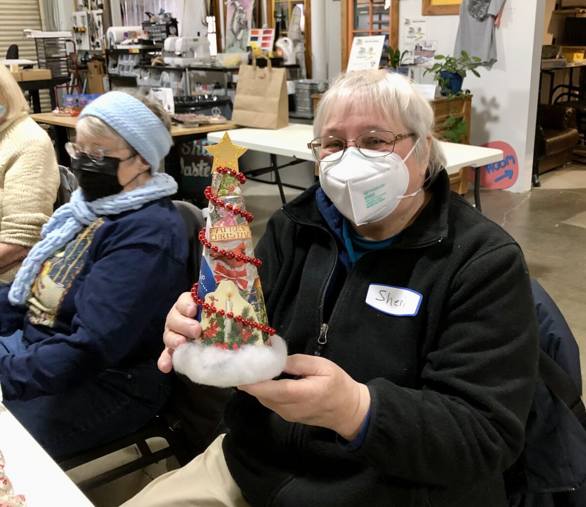 a member of the Collage Guild is holding a colorful handmade christmas tree